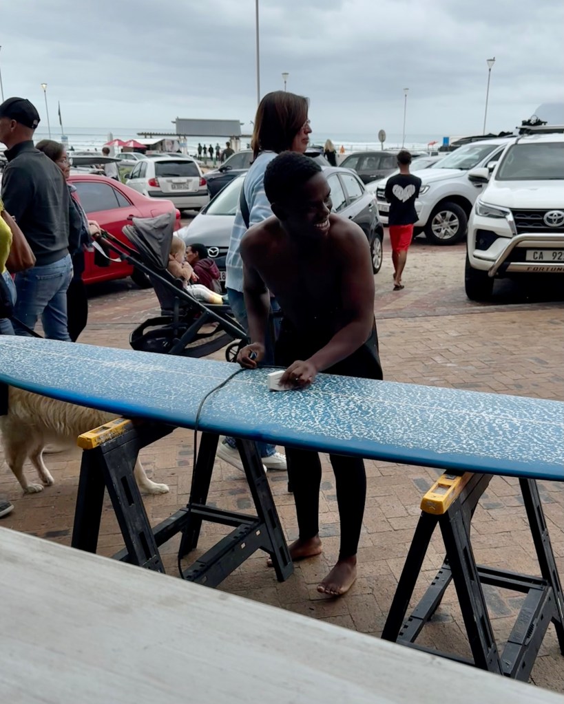 Surfer waxing his longboard before going for a surf