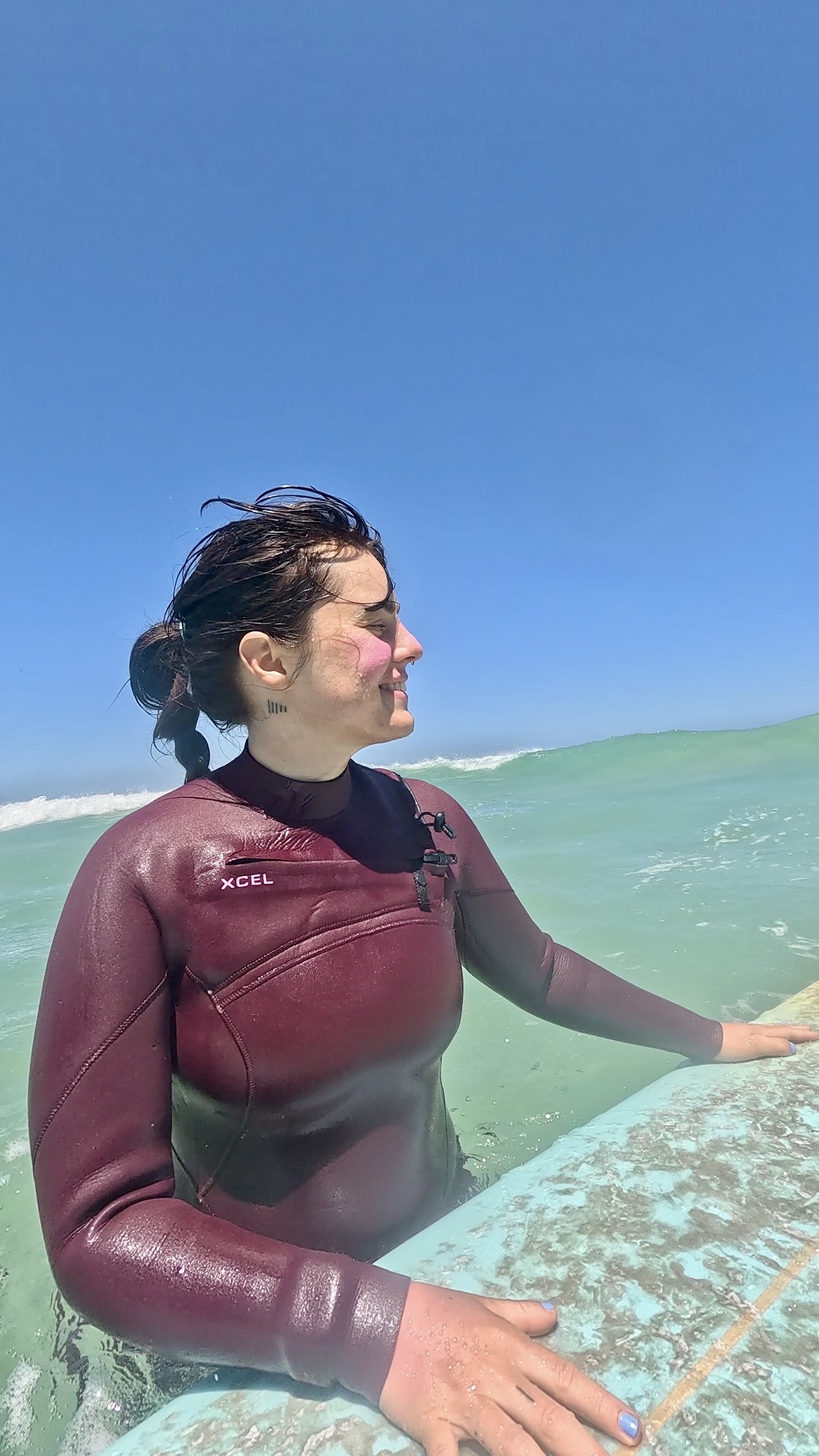 Female surfer happy in the water with her surfboard during a surf lesson